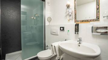 Une salle de bain moderne avec une douche à parois de verre, un lavabo blanc et un grand miroir.