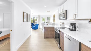 A modern kitchen with white cabinets, stainless steel appliances, and a marble countertop. - NEW LISTING! Village Breeze - Heated Pool, Private Patio, Village and Beach! (Siesta Key)
