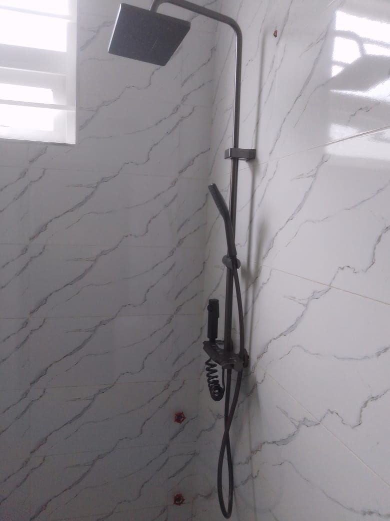 A shower with a handheld showerhead and a fixed wall-mounted showerhead, mounted on a marble wall.
