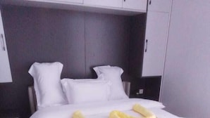 A modern bedroom with a large bed, white bedding, and a wooden floor. - Migori Executive Residence  (Migori)