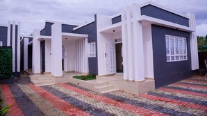A modern two-story house with a dark facade and white accents, featuring a tiled entrance and a small garden area. - Migori Executive Residence  (Migori)