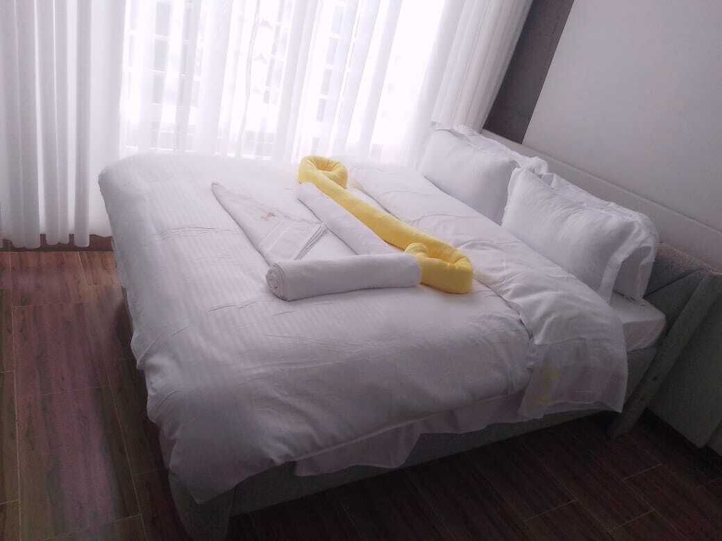 A neatly made bed with white bedding and a yellow towel.