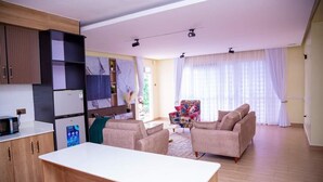 A modern living room with a sofa set, a coffee table, and a dining area with a white table. - Migori Executive Residence  (Migori)
