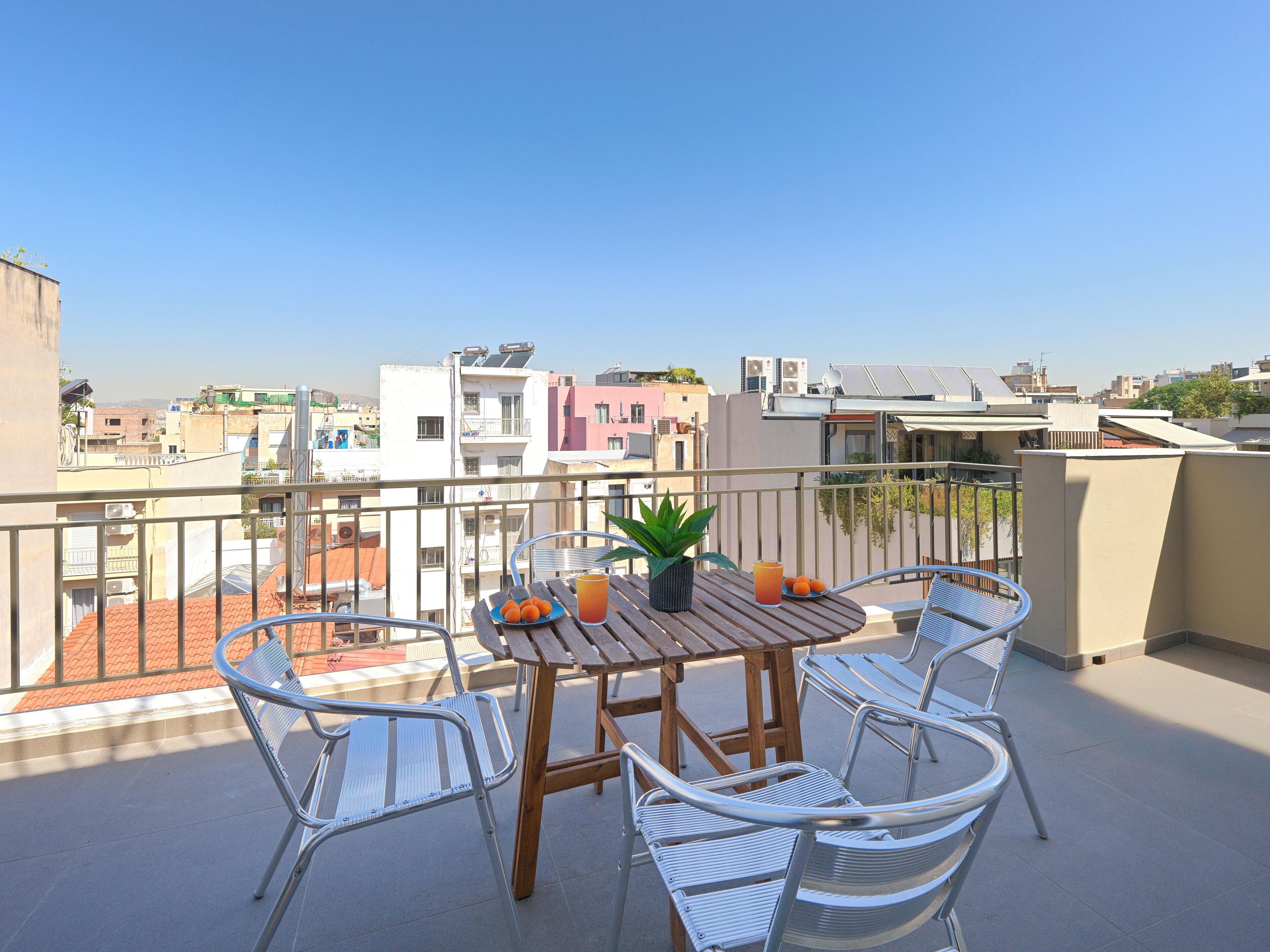 Un balcon avec une table et des chaises, un pot de fleurs et une assiette remplie d’oranges.