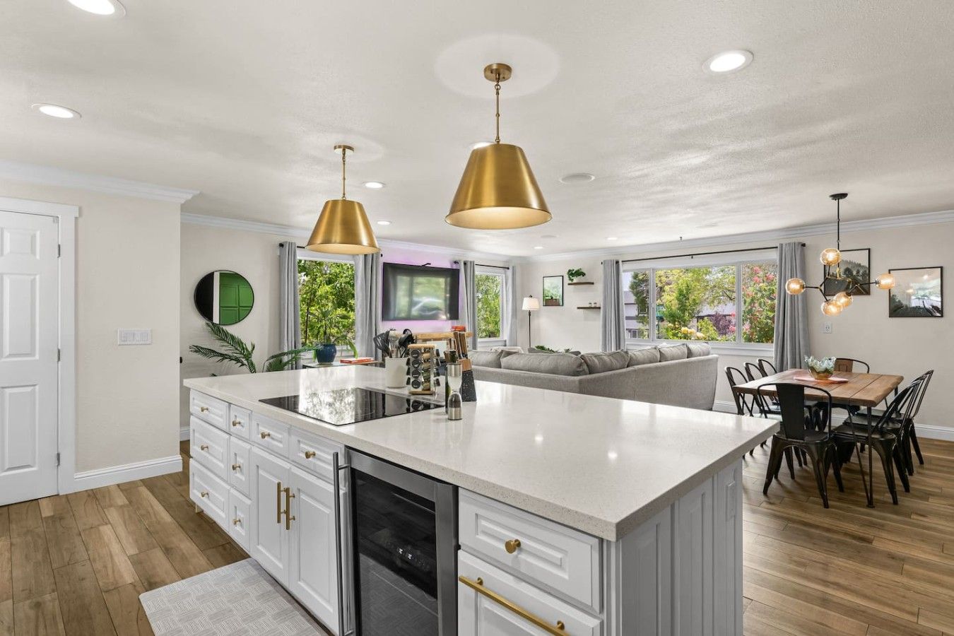 A modern kitchen with a central island, white cabinetry, and gold pendant lighting.