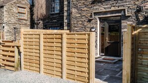 A stone building with a wooden gate and a stone entrance. - Ground floor apartment, central Ambleside, parking and a dog. (Ambleside)