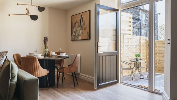 A dining area with a table set for four, a sofa, and a painting on the wall. - Ground floor apartment, central Ambleside, parking and a dog. (Ambleside)
