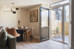 A dining area with a table set for four, a sofa, and a painting on the wall.