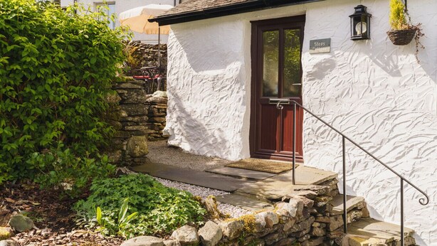 Un bâtiment blanc avec un escalier en pierre menant à une porte en bois.