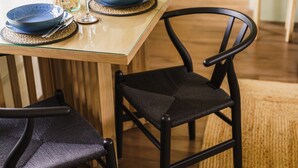 Une table à manger avec des assiettes bleues et un verre, accompagnée de chaises noires.
