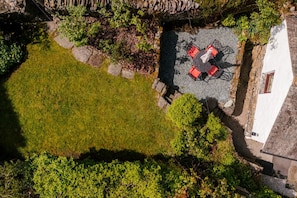 An aerial view of a courtyard with a seating area, stone walls, and surrounding greenery.