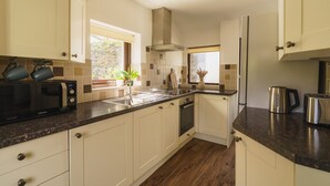 Une cuisine moderne avec des meubles blancs, un plan de travail noir et des appareils électroménagers en acier inoxydable.