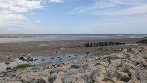 A rocky beach with waves, a clear sky, and distant structures. - Vacation home for 2 people at the campsite in Wremen (Wurster Nordseeküste)