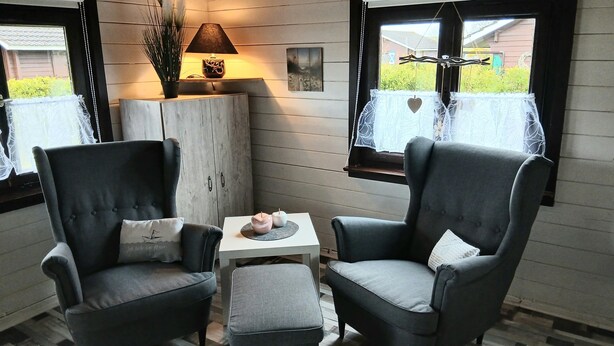 A cozy corner with two grey armchairs, a small white table, and a lamp. - Vacation home for 2 people at the campsite in Wremen (Wurster Nordseeküste)