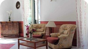 A living room with two armchairs, a wooden coffee table, and a sideboard.