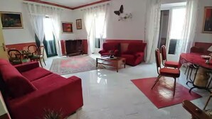 A living room with a red sofa, a wooden coffee table, and a dining area with a table and chairs.