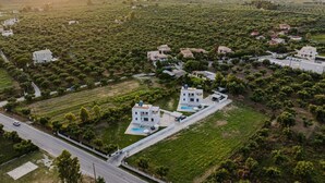 An aerial view of a residential area with houses, a road, and a large open field.