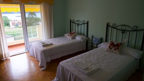 A room with two single beds, a small table, and a window with curtains. - HOUSE WITH SWIMMING POOL AND SEA VIEWS IN MIÑO (Perbes)