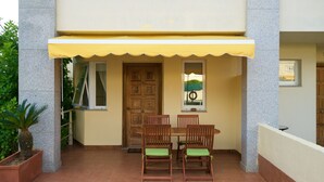 A patio with a table and chairs, a yellow awning, and a wooden door. - HOUSE WITH SWIMMING POOL AND SEA VIEWS IN MIÑO (Perbes)