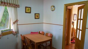 A dining area with a wooden table and chairs, a window with curtains, and two wall-mounted clocks. - HOUSE WITH SWIMMING POOL AND SEA VIEWS IN MIÑO (Perbes)