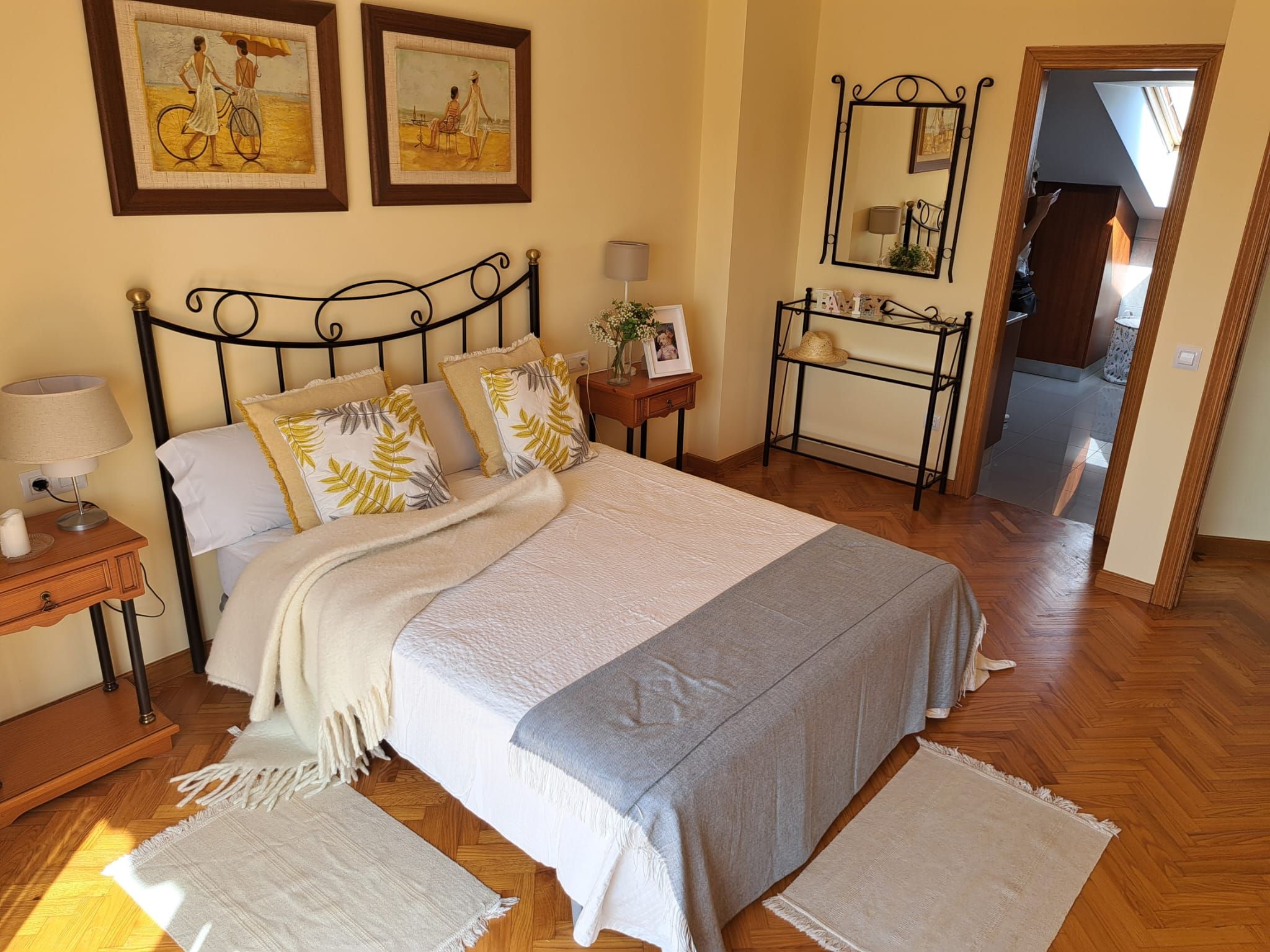 A bedroom with a bed, bedside tables, a mirror, and artwork on the wall.