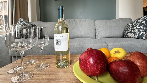 A room with a wooden table, a bottle of wine, and a plate of fruit. - Bosphorus View Duplex in Central Istanbul  2BR  Sleeps 6 (Istanbul)