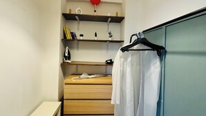 A compact room with a wooden dresser, a hanging light fixture, and a clothing rack. - Bosphorus View Duplex in Central Istanbul  2BR  Sleeps 6 (Istanbul)