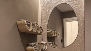 Une salle de bain avec un grand miroir, un lavabo en osier et un distributeur de serviettes.