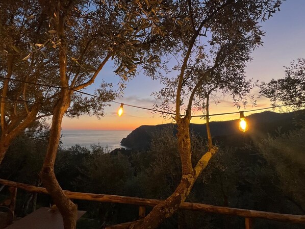 Vista del atardecer con luces colgantes y barandilla de madera.