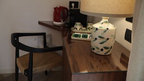 Une petite pièce moderne, équipée d’un bureau en bois, d’une chaise, d’une lampe et d’une machine à café.