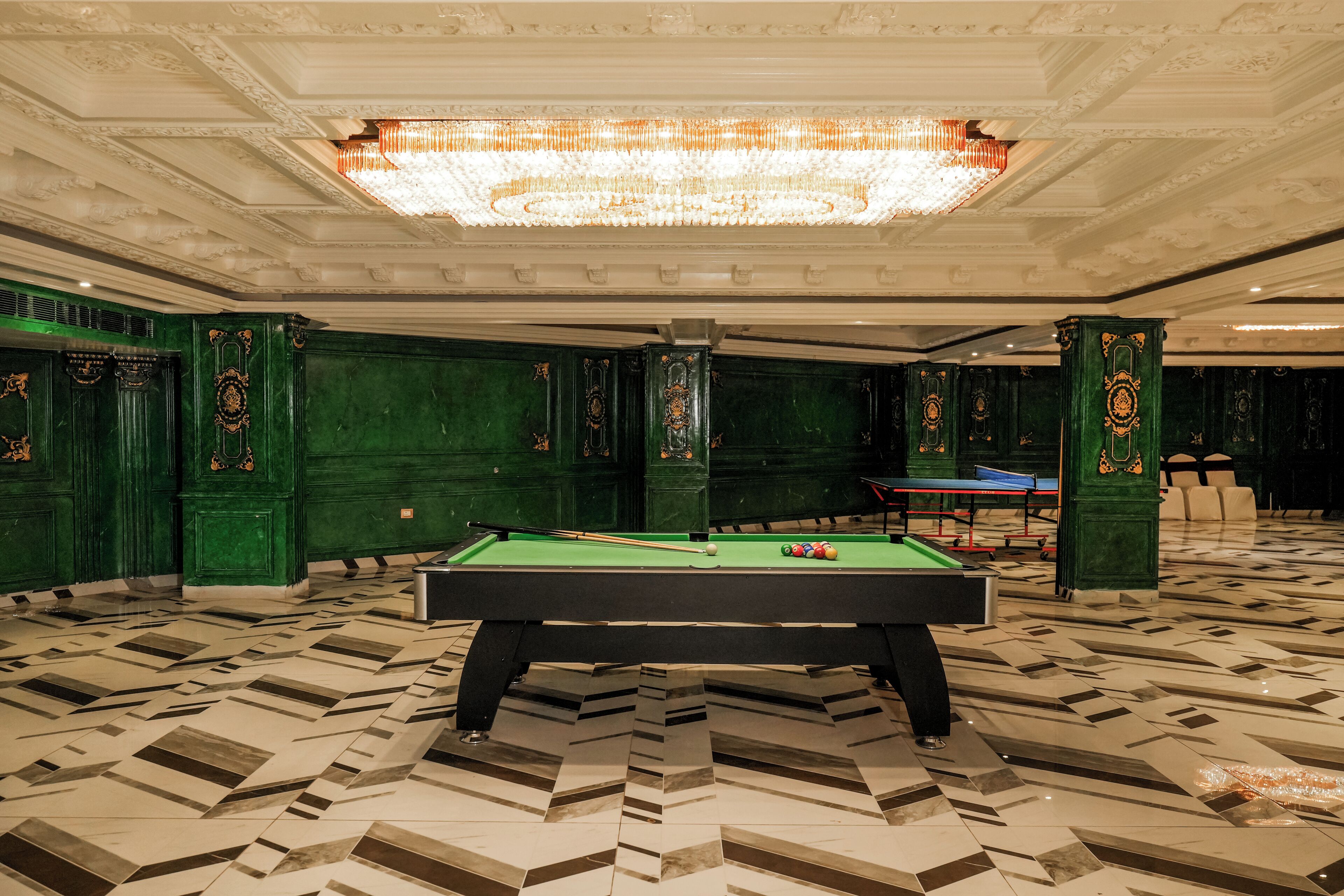 A pool table in a room with green walls and a patterned floor.