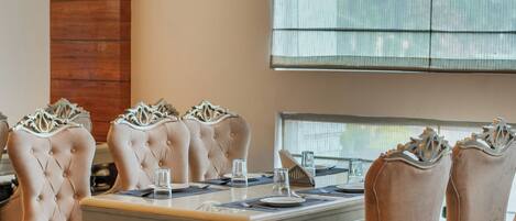 A dining area with a large table, six upholstered chairs, and a patterned floor.