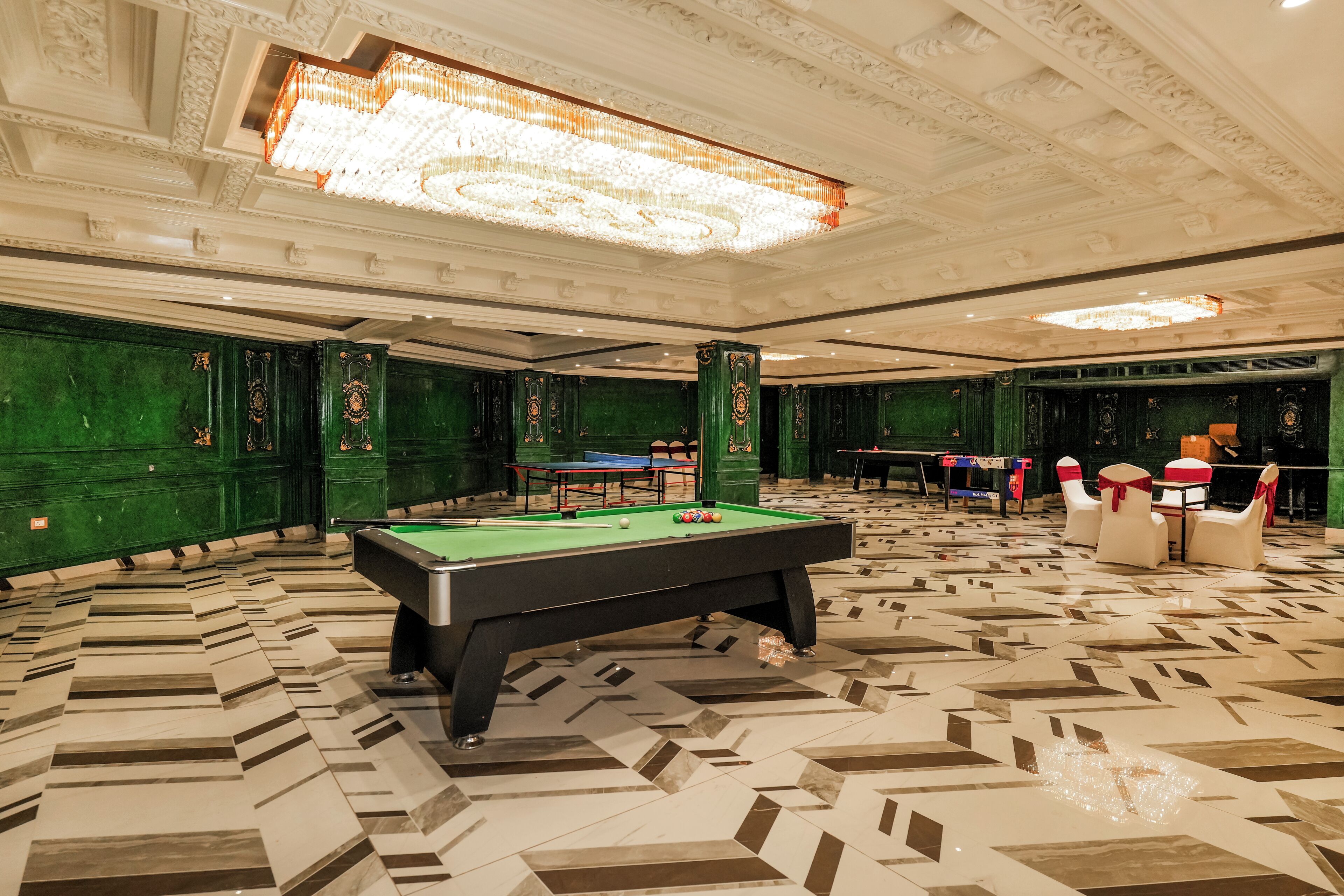 A billiards room with a pool table, green walls, and a patterned floor.
