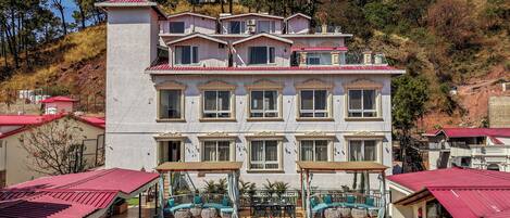 A multi-story hotel with a courtyard featuring outdoor seating and tables.