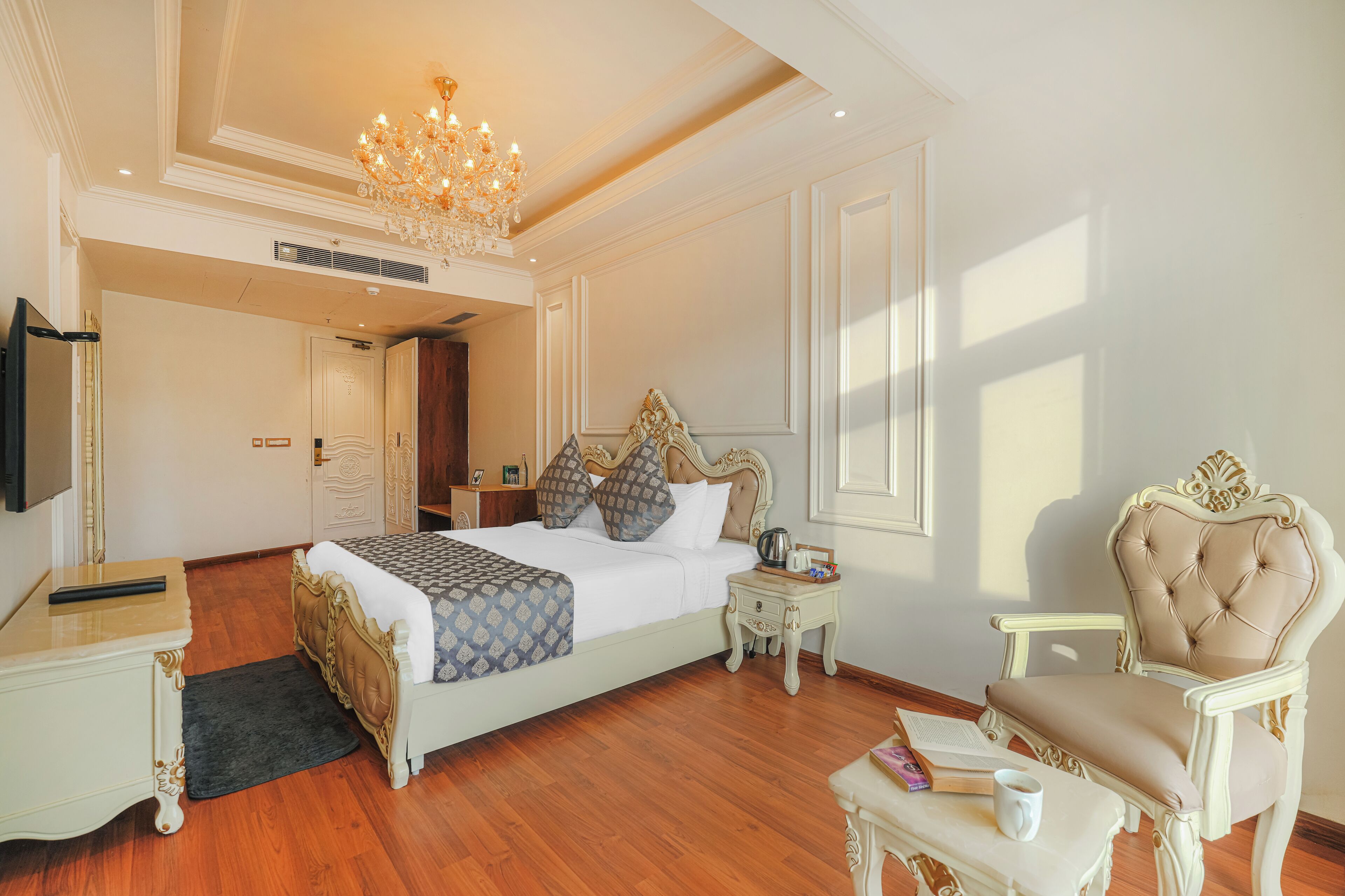 Un dormitorio amplio con una cama grande, una zona de estar con un sillón, una mesita de noche y un televisor.