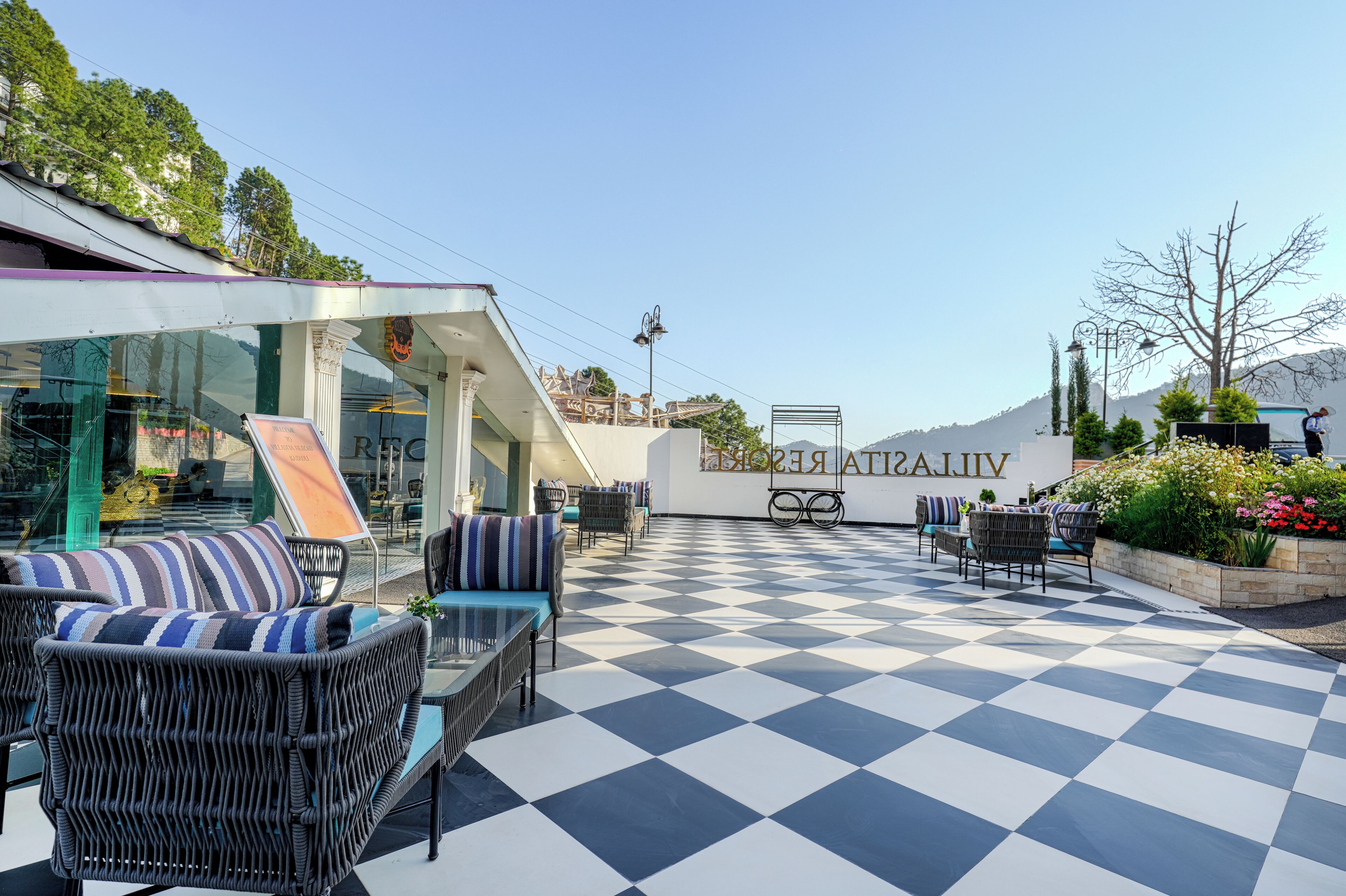 A terrace with checkered flooring, wicker furniture, and a sign reading "ASTRAJIV."