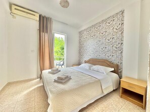 A bedroom with a bed, a nightstand, a window with curtains, and a patterned wallpaper. - B&M Holiday Rooms (Prijevor)