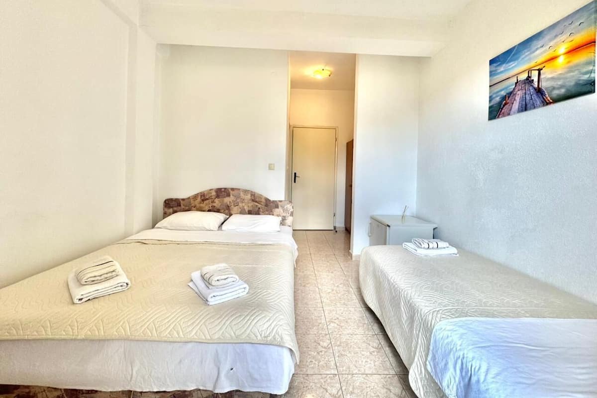 Een hotelkamer met twee bedden, een schilderij aan de muur en een deur naar een andere kamer.