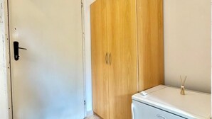 Ein Zimmer mit einer weißen Tür, einem Holzschrank und einem weißen Gerät auf dem Boden.