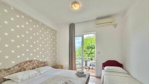 Ein Hotelzimmer mit zwei Betten, einer Wand mit Sternenmuster, einem Balkon mit Tisch und Stühlen sowie einer Klimaanlage.
