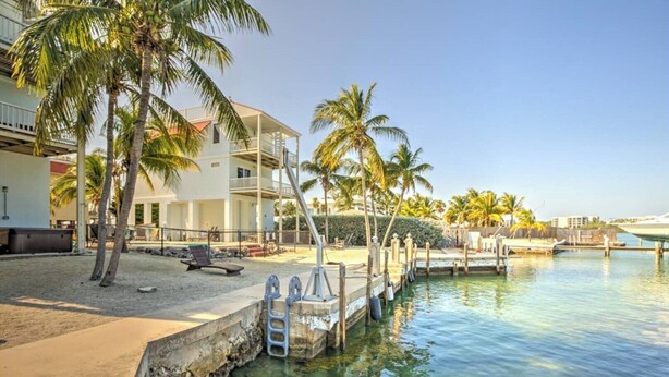 A waterfront property with a pool, palm trees, and a dock.
