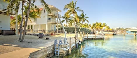 A waterfront property with a pool, palm trees, and a dock.