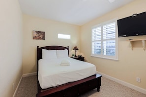 A bedroom with a bed, a nightstand, a lamp, a TV, and a window with blinds. - Relaxing 3 Bdr Keys Retreat - Hate to leave it (Marathon)