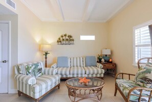 A living room with striped sofas, a glass coffee table, and a starfish decoration.