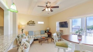 A living room with a sofa, chairs, a dining table, a ceiling fan, and a TV mounted on the wall. - Relaxing 3 Bdr Keys Retreat - Hate to leave it (Marathon)