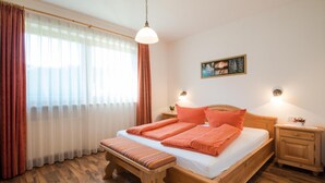 A bedroom with a wooden bed, a bench, a nightstand, and a wall-mounted light. - Apartment 'Sonnenblume' with Mountain View, Wi-Fi and Air Conditioning (Lagundo)