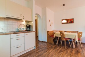 Una cocina con armarios blancos, encimera de madera y zona de comedor con mesa y sillas.