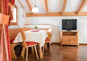 A dining area with a table, chairs, a television, and a cabinet.