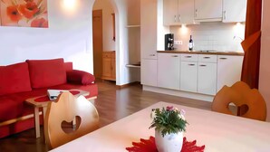 A modern living room with a red sofa, a wooden coffee table, and a painting on the wall. - Apartment 'Mohnblume' with Mountain View, Wi-Fi and Air Conditioning (Lagundo)