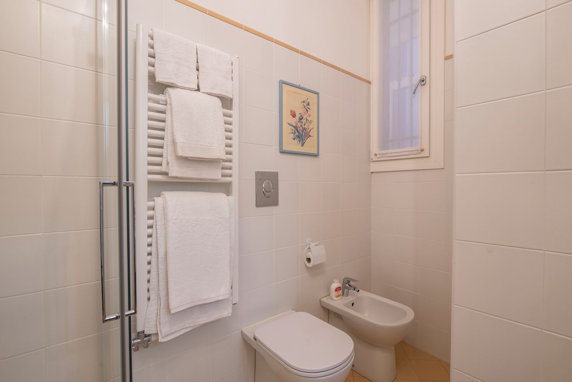 Et badeværelse med toilet, bidet og et håndklædestativ.